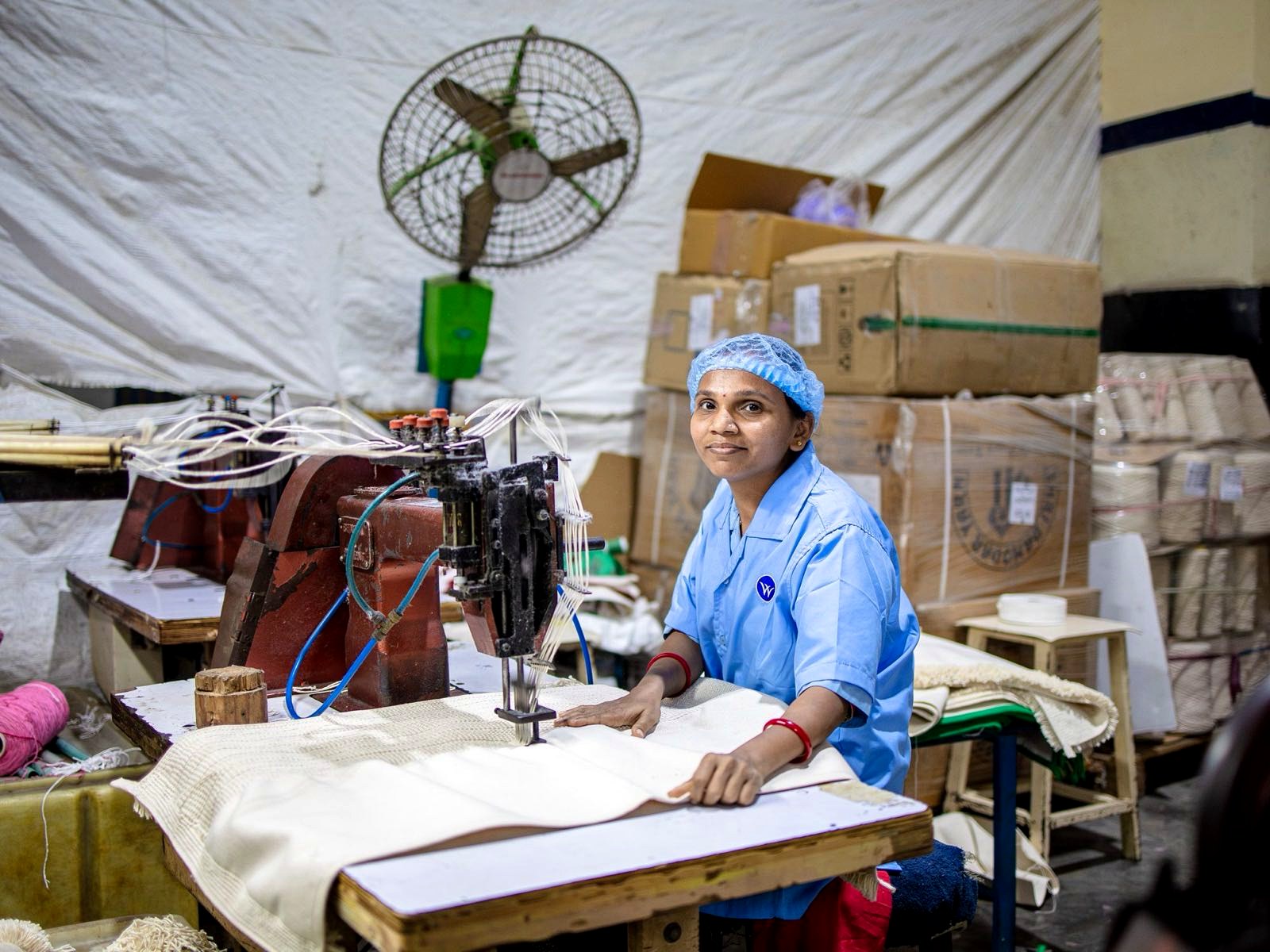 Machine operator sewing fabric on a garment factory floor