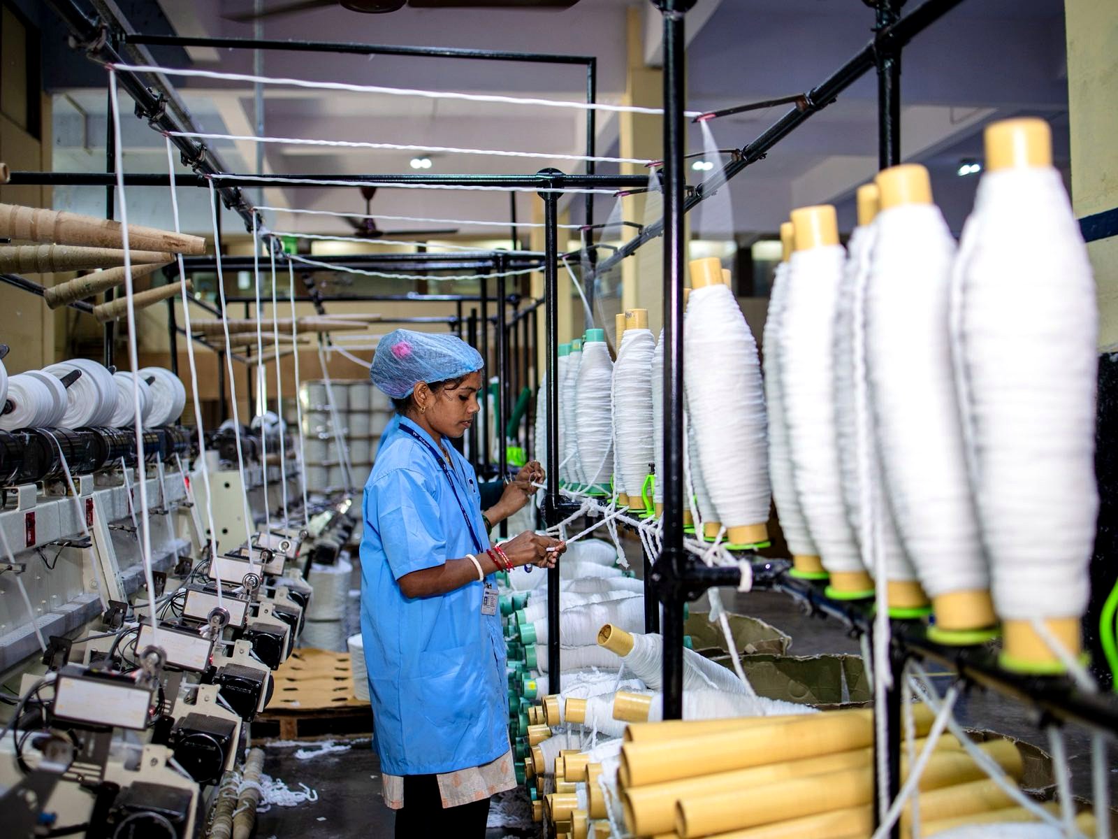 Factory worker operating spinning machinery in a textile mill